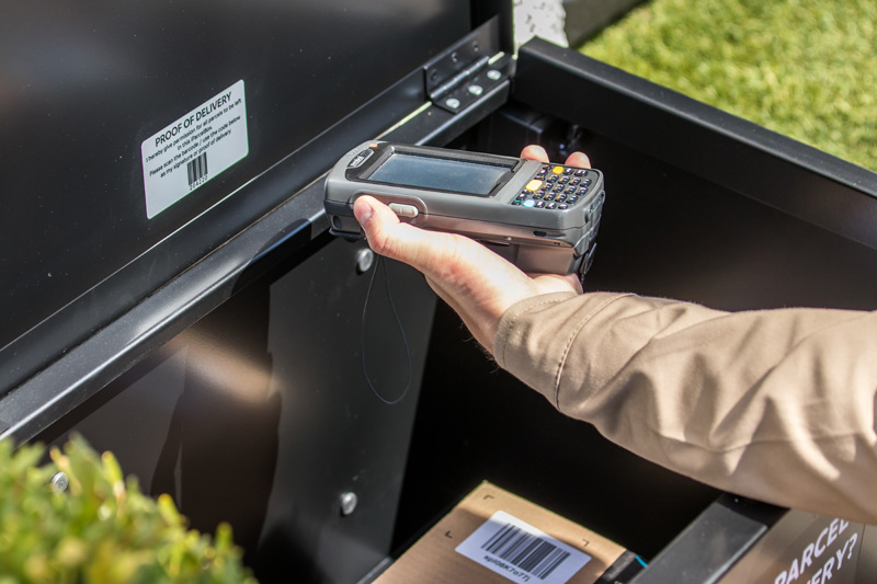 Courier is scanning the unique barcode on the inside lid of the iParcelBox smart parcel delivery box as proof of delivery.