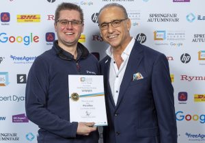 Photo showing iParcelBox founder Paul Needler being handed his #SBS certificate by Theo Paphitis in recognition of our smart parcel delivery box being selected as winners of his Small Business Sunday competition.